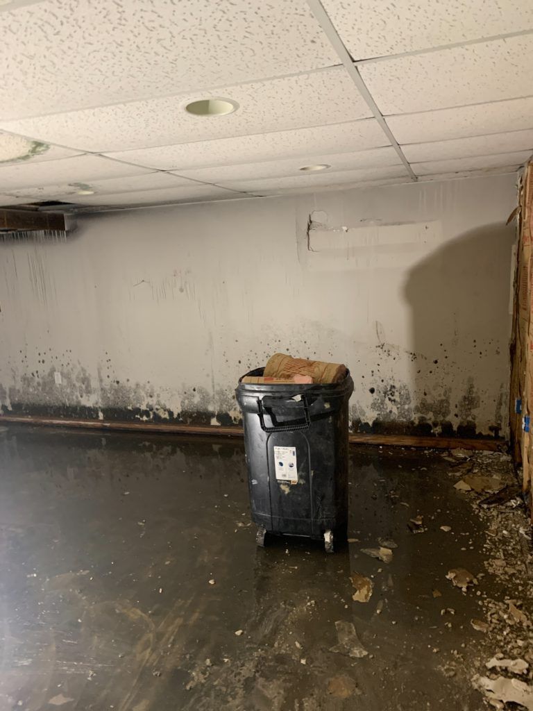 A trash can is sitting in the middle of a flooded room.