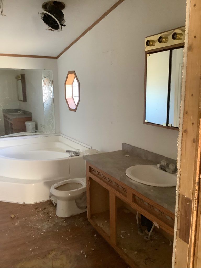 A bathroom with a tub, toilet, sink and mirror.