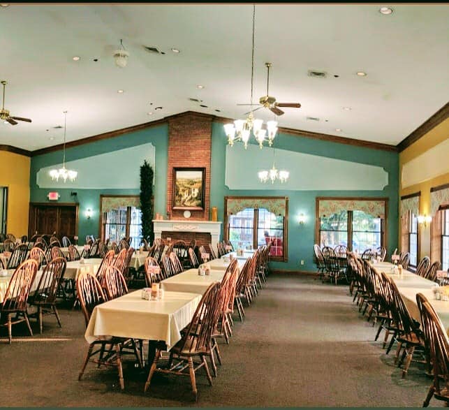 A large dining room with allot of tables, chairs, and a fireplace.