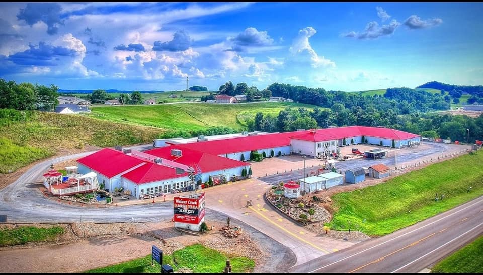 An aerial view of a very large building with a red roof in the middle of a field.
