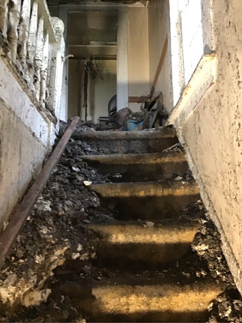A set of stairs with fire damage leading up to a room in a home.