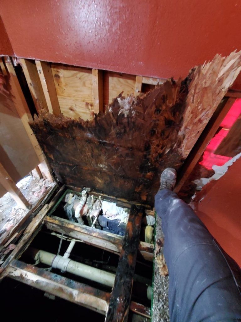 A person is standing in a hole in the floor of a building.