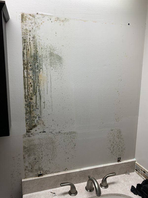 A bathroom with a dirty mirror and a sink inside damaged house.