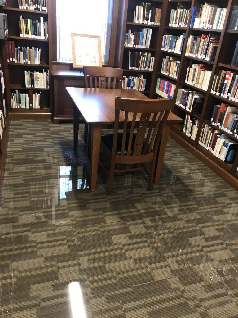 A library with a table and chairs surrounded by bookshelves