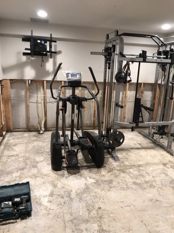 A basement gym with a lot of exercise equipment.