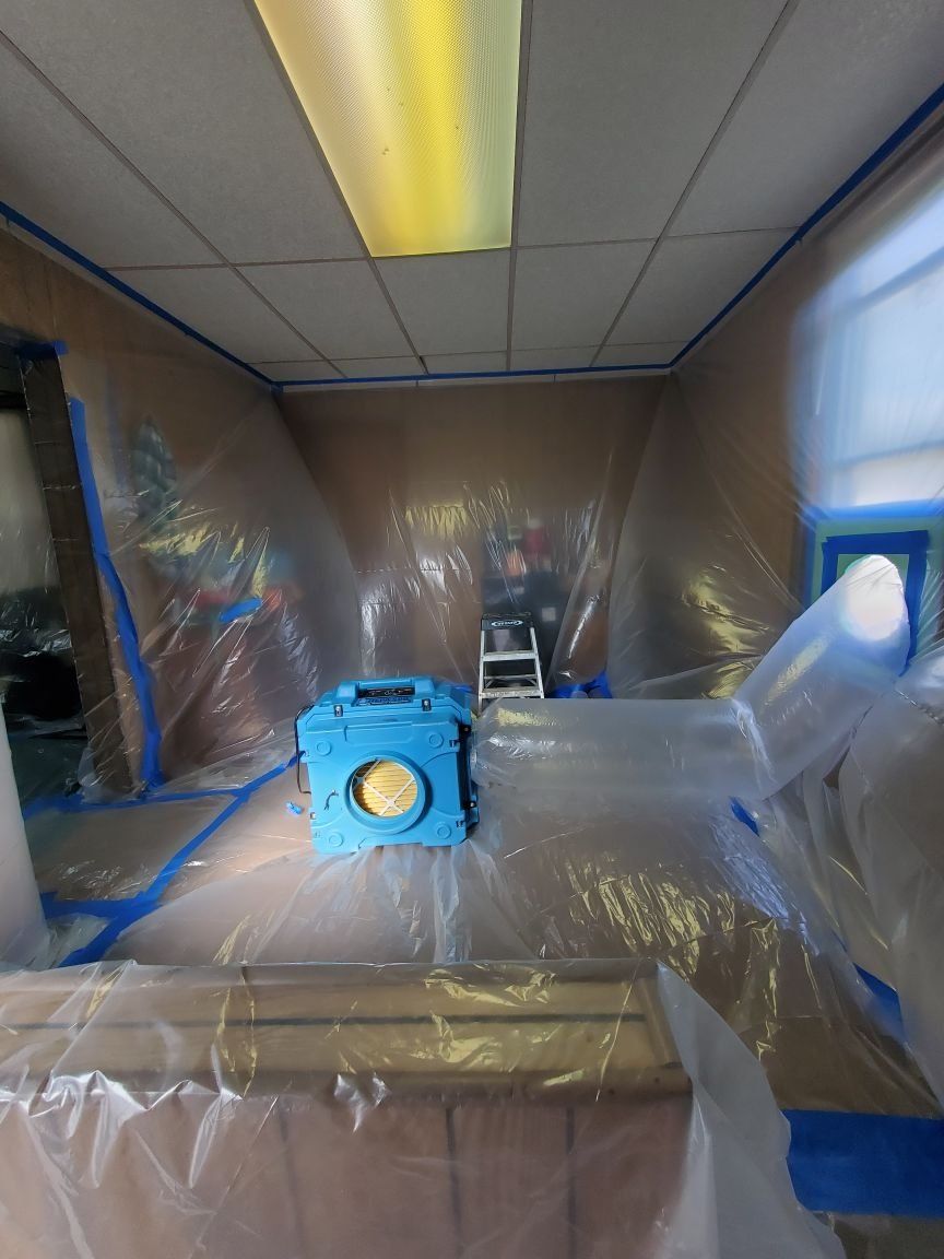 A room is covered in plastic and has a blue machine in it.
