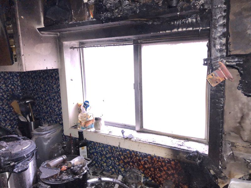 A kitchen with a window that has been damaged by fire