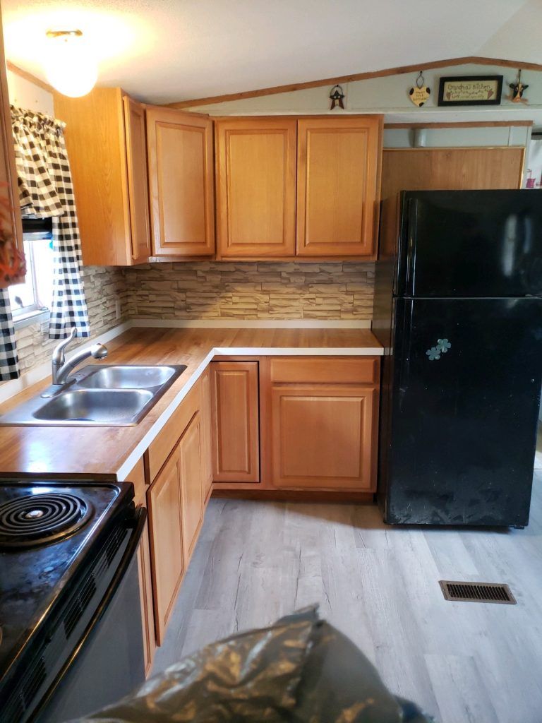 A kitchen with wooden cabinets and a black refrigerator