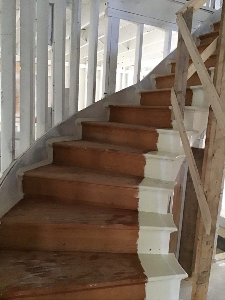 A wooden staircase with white steps and a white railing
