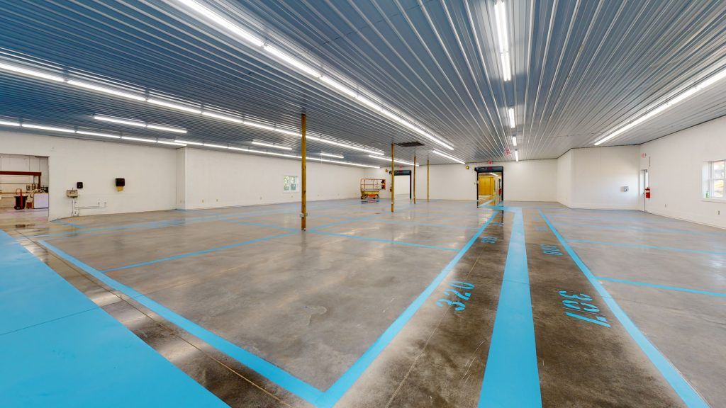 A large empty warehouse with blue lines and numbers on the floor.