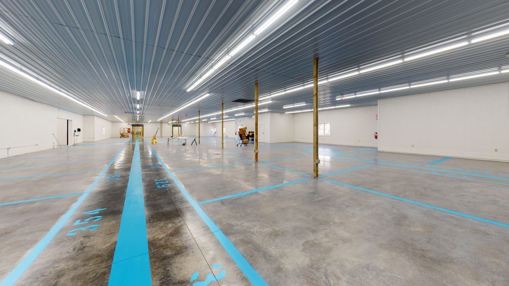 A large empty warehouse with blue lines and numbers on the floor.