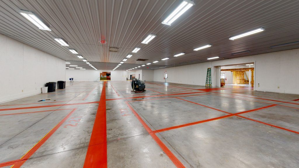 A large empty warehouse with red lines and numbers on the floor.