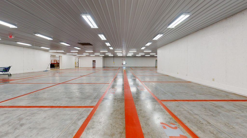 A large empty warehouse with orange lines and the numbers 21 on the floor.