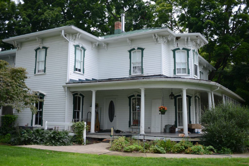 A white house with green trim and a porch.