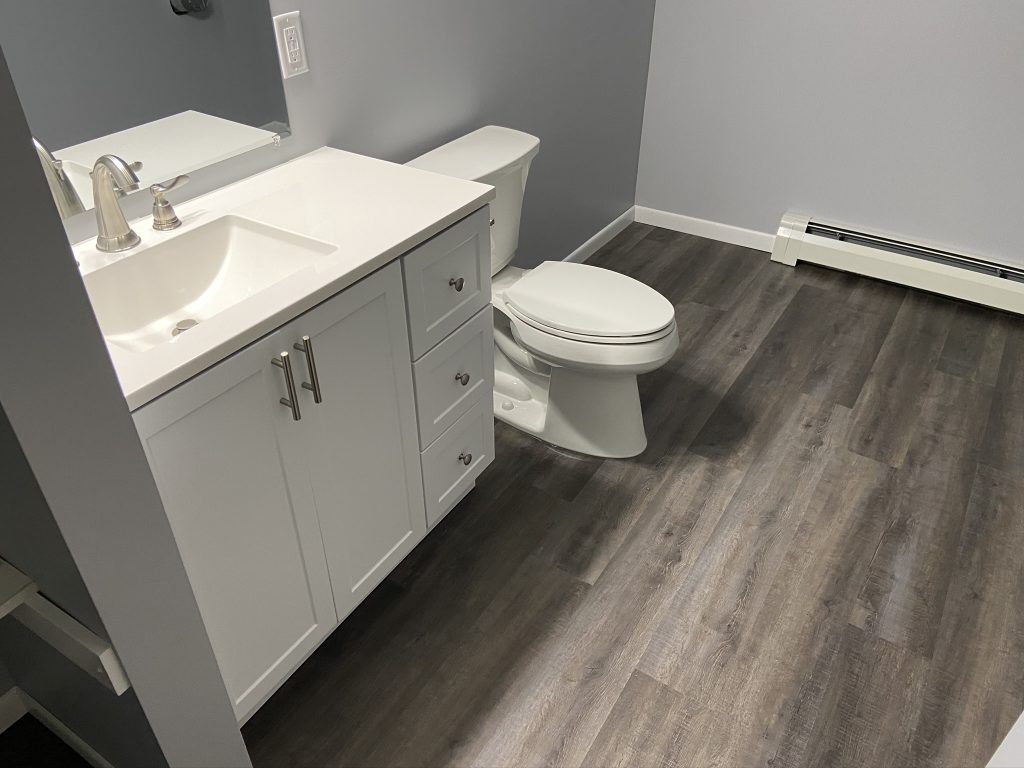 A bathroom with a toilet, sink, and mirror.