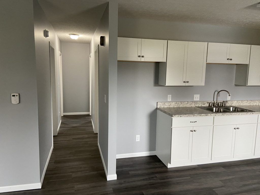 An empty kitchen with white cabinets and a sink