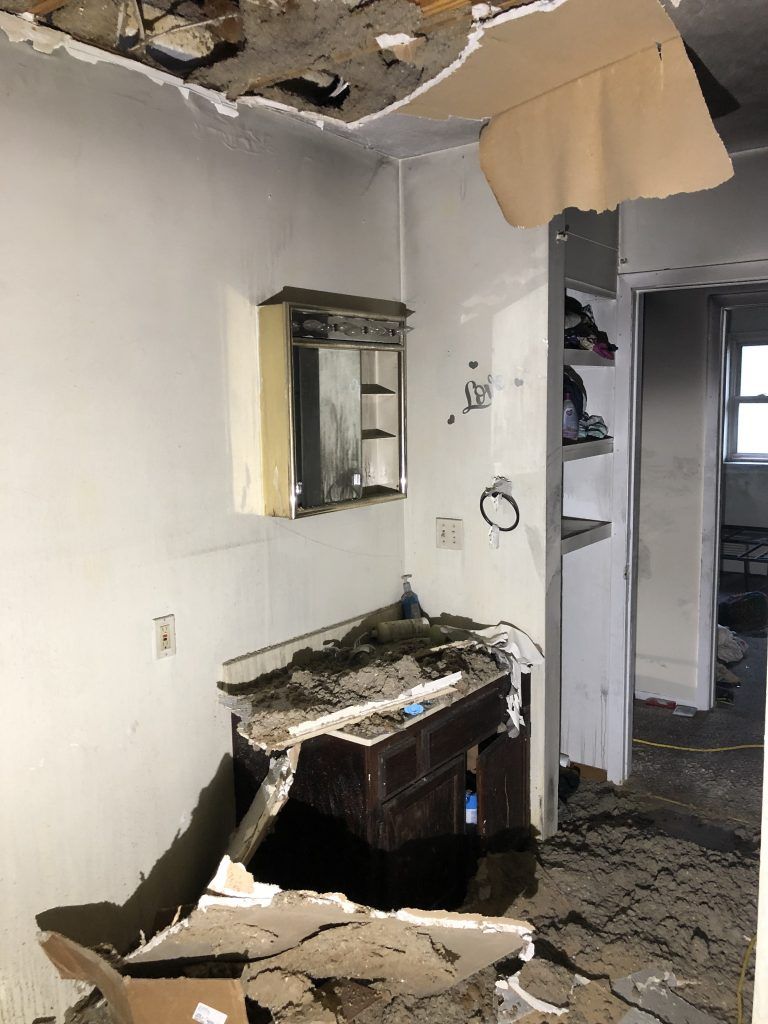 A bathroom in a fire damaged house with a sink and a mirror.