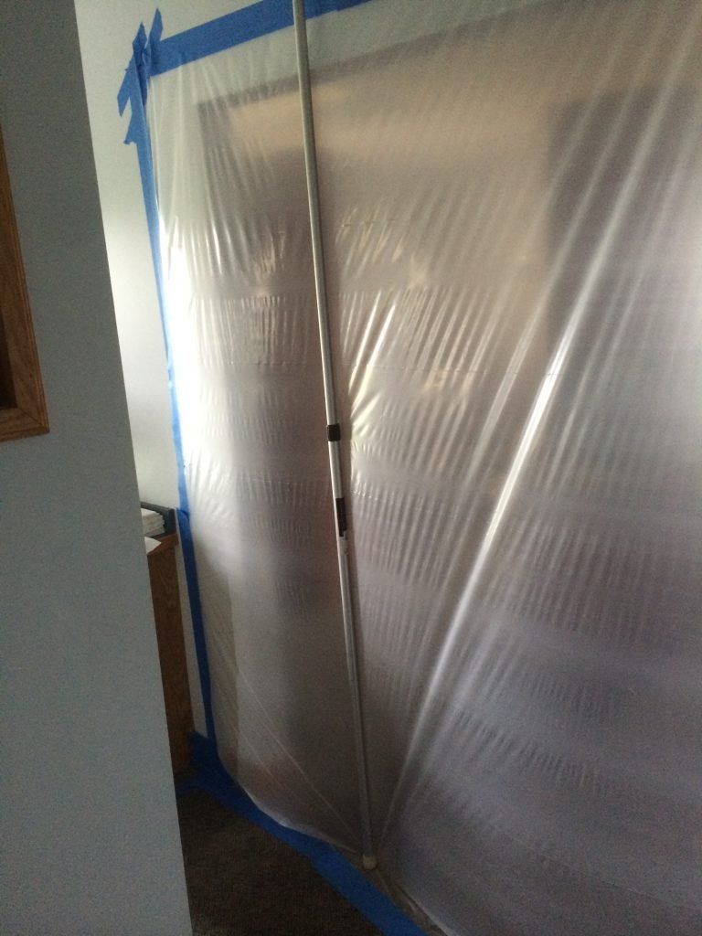 A plastic tarp is covering a door in a room.