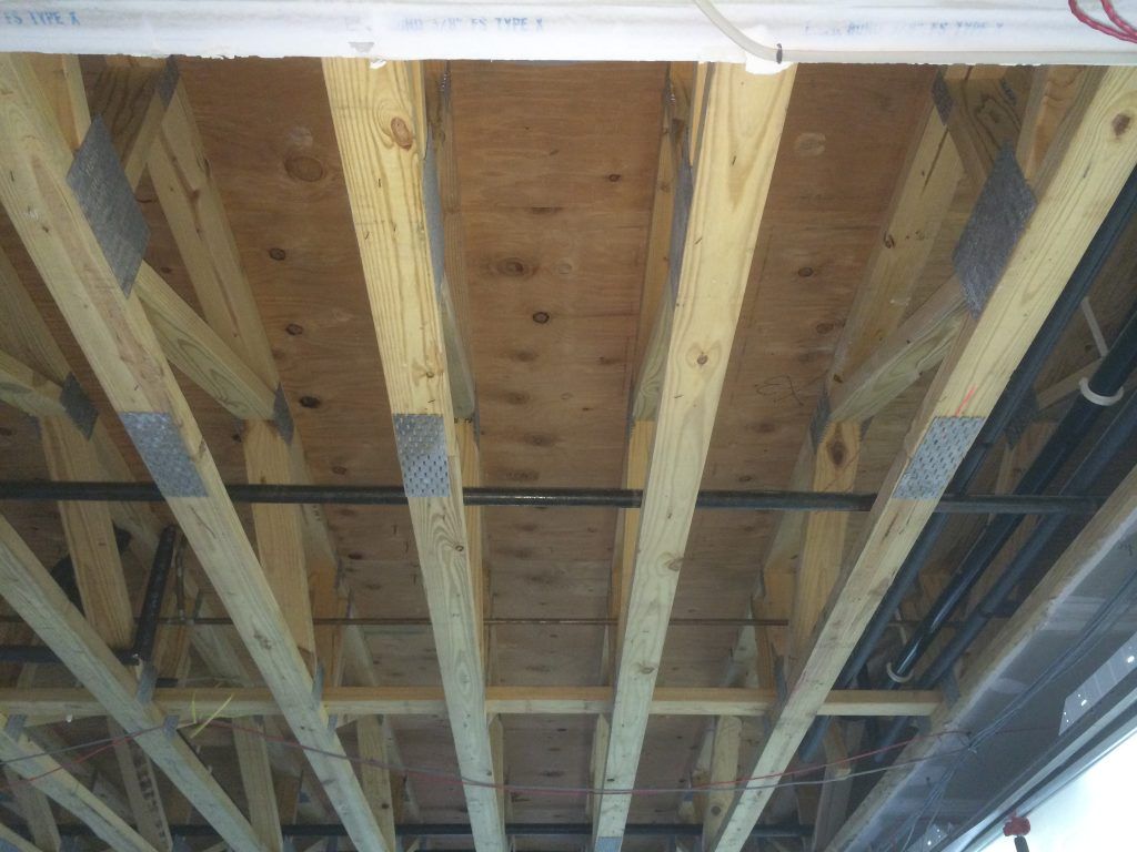 A ceiling with a lot of wooden beams and pipes.