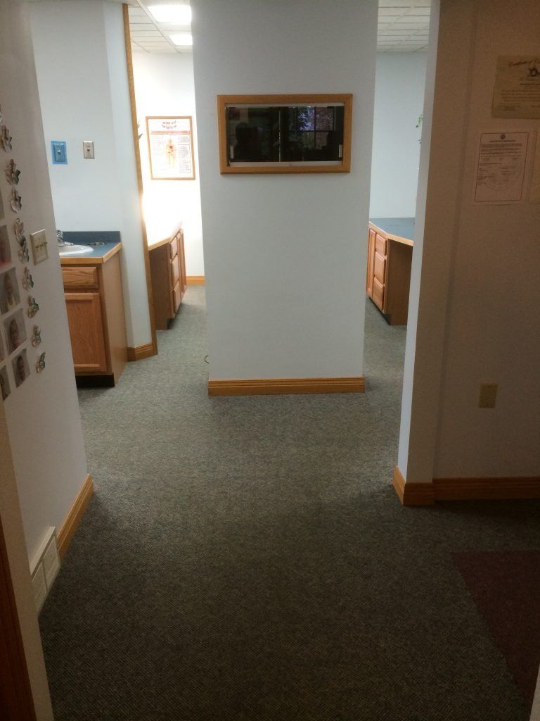 A hallway in an office with a mirror on the wall.