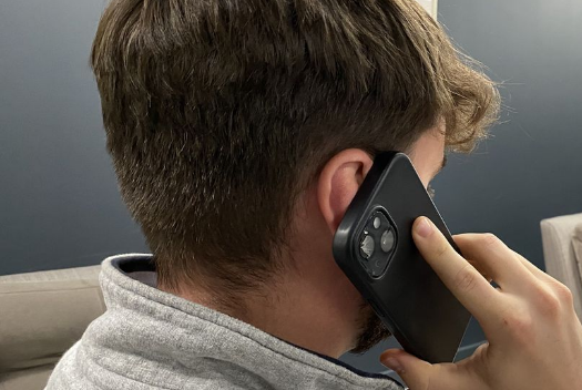 A man is talking on a cell phone while sitting on a couch.