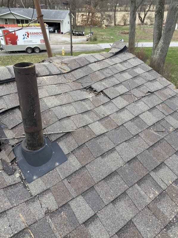 There is a chimney on the damaged roof of a house.