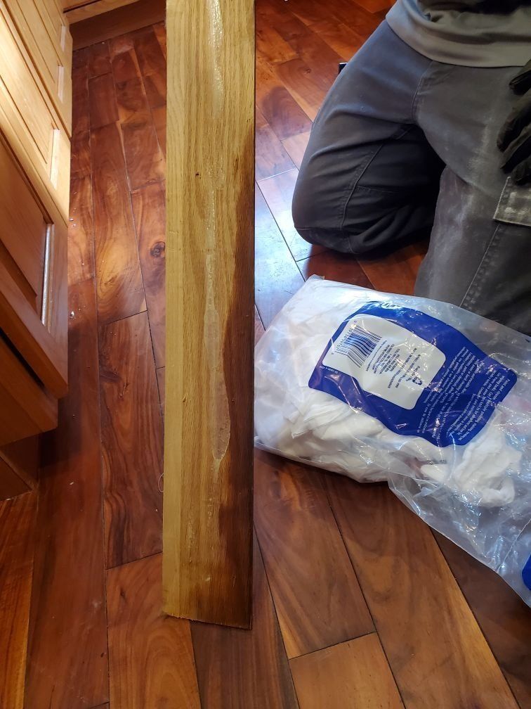 A person is kneeling on the floor next to a bag of mop heads.