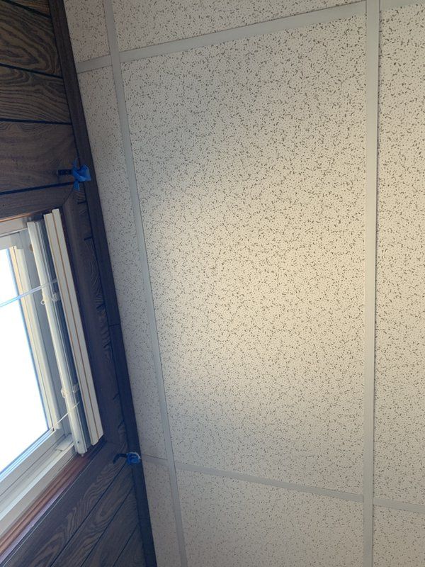 A white tile ceiling with a window in the corner.