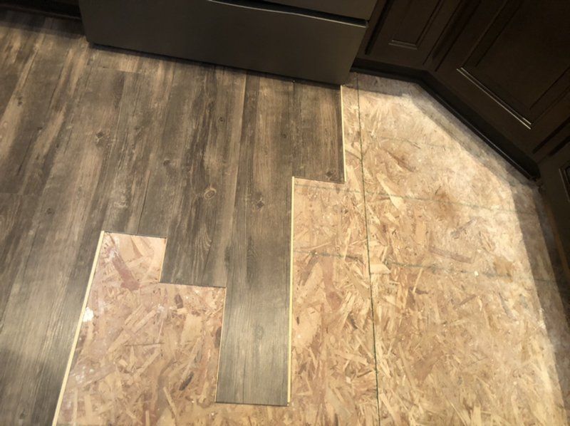 A kitchen with a wooden floor and a stainless steel refrigerator.