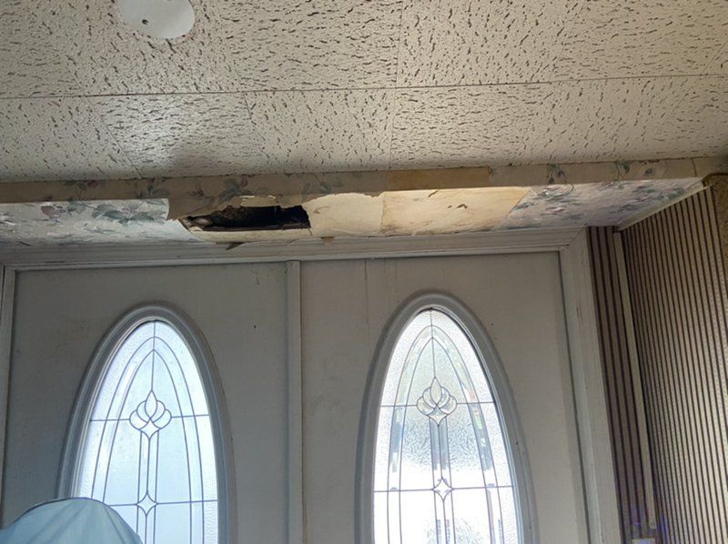 Two doors with water damaged ceiling above it.