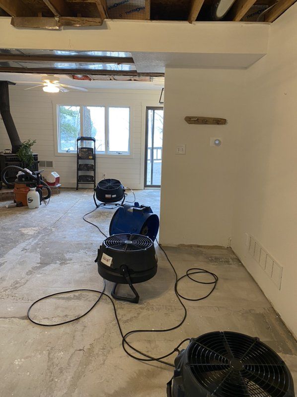 A room with an industrial fan and vacuum in it.