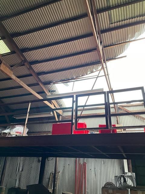 A warehouse with a balcony and a metal roof.