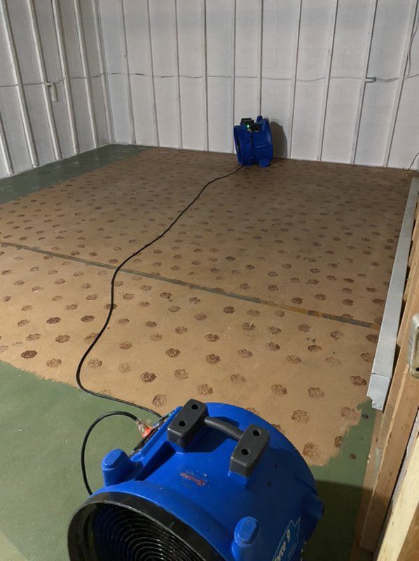 A blue industrial fan is sitting on the floor of a room.