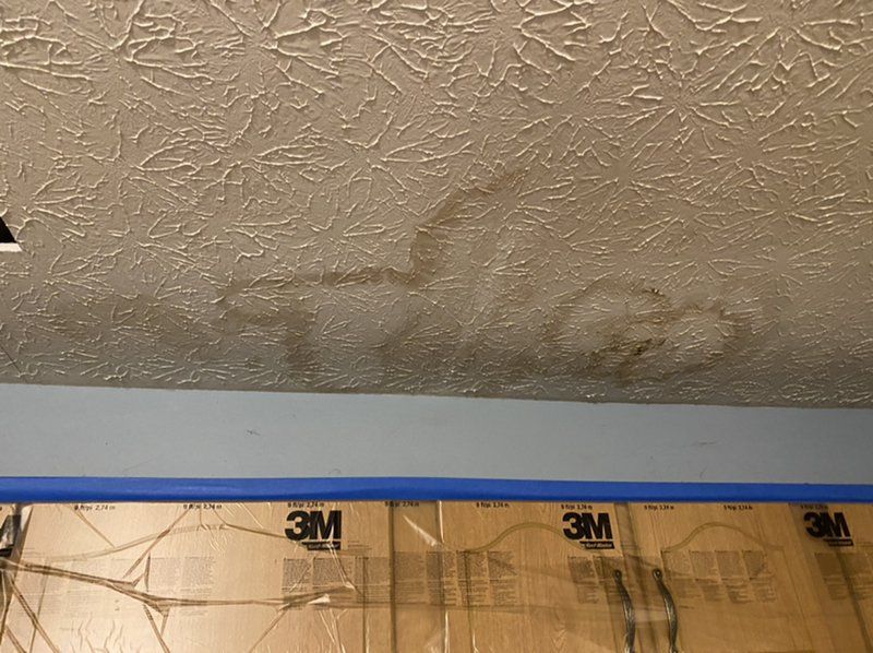A water damaged ceiling with a piece of 3m tape on it.