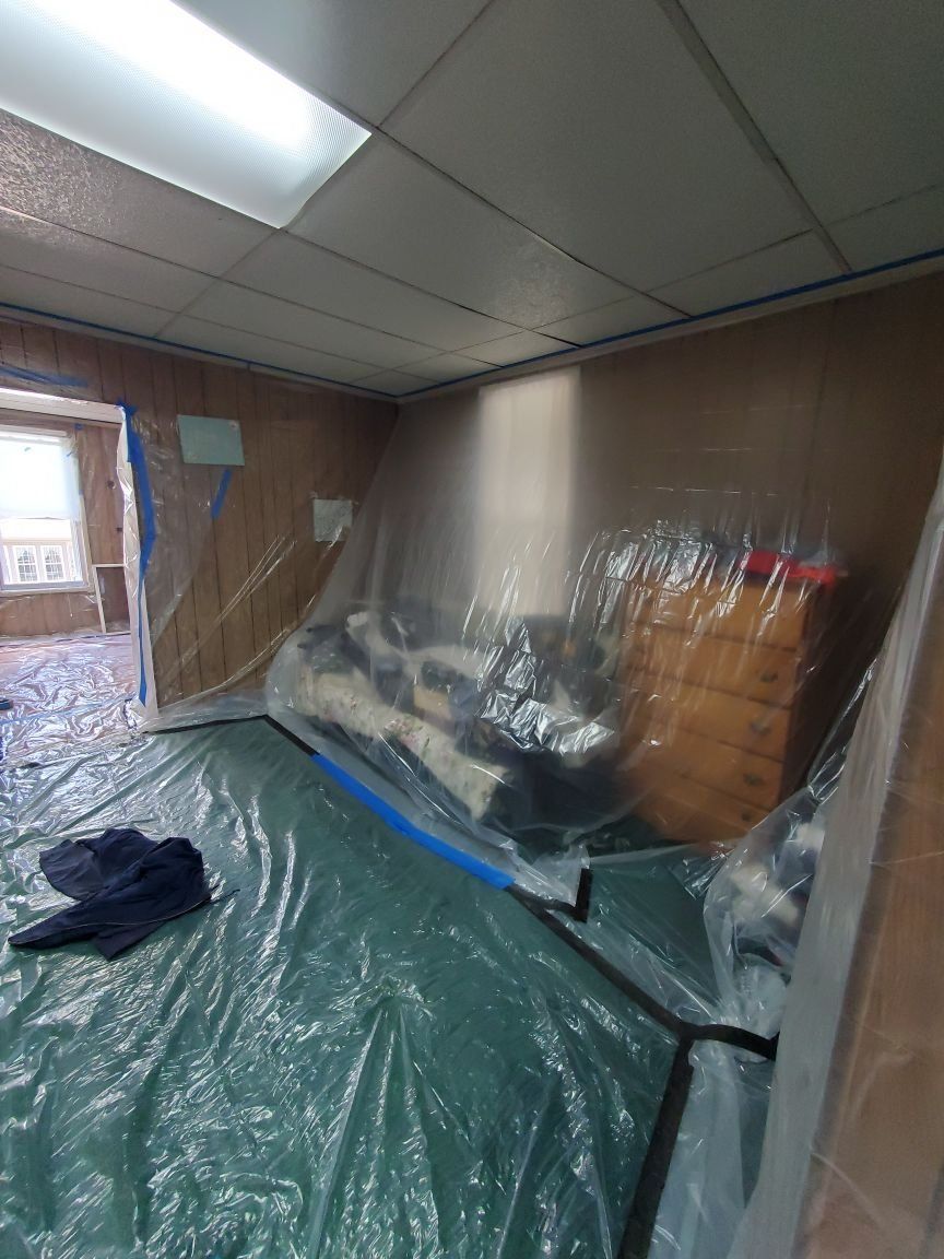 A room with a couch and dresser covered in plastic.