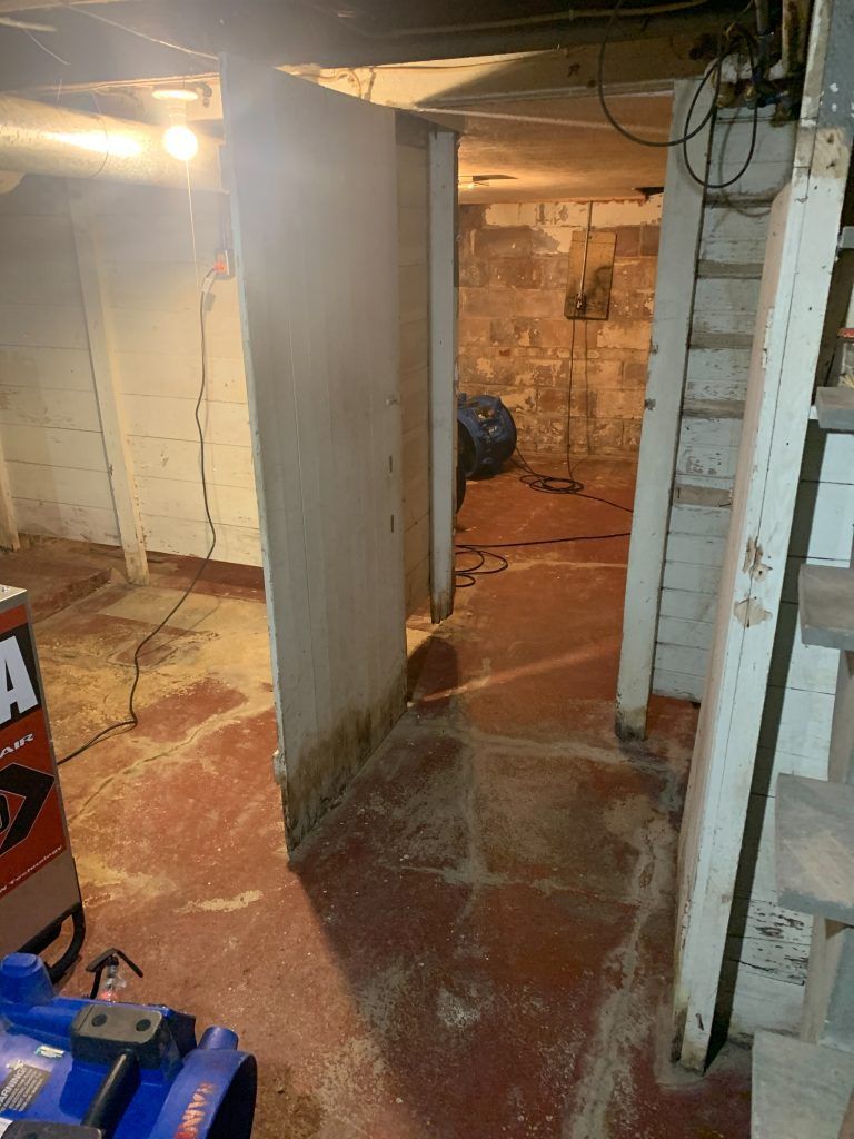 A water damaged basement with a staircase leading up to the second floor.