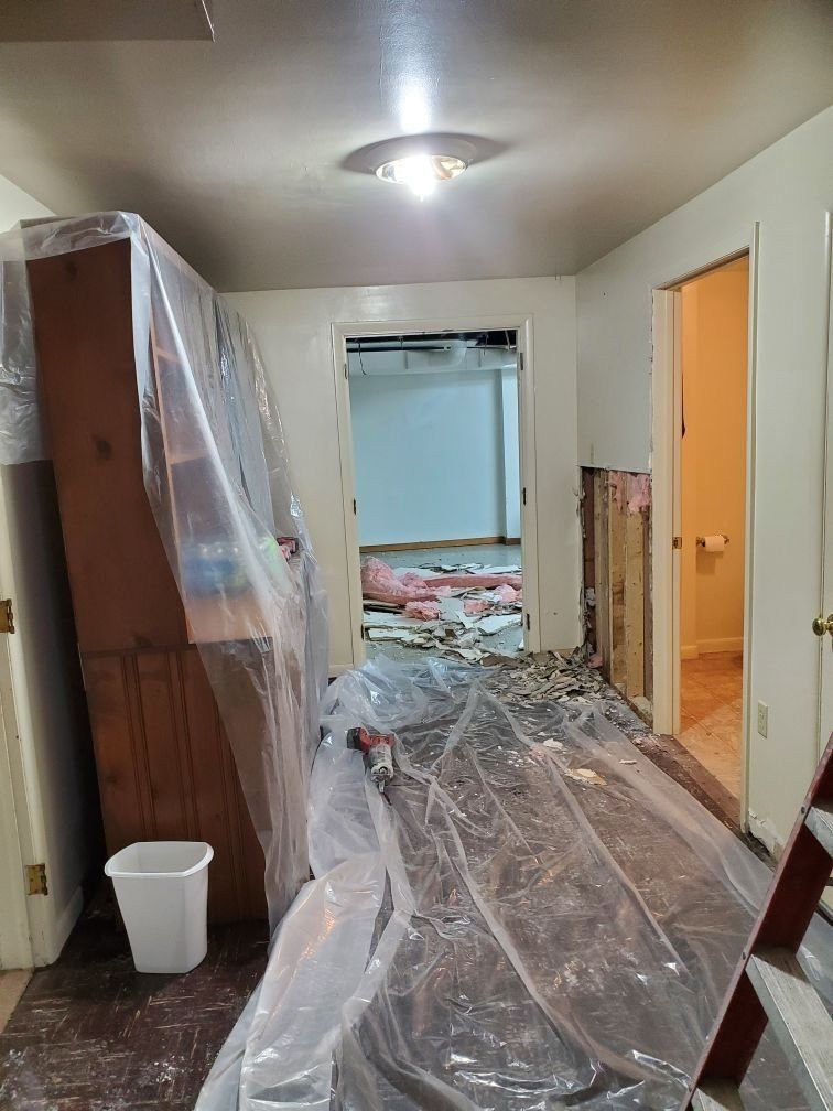 A room with a dresser and a trash can covered in plastic.