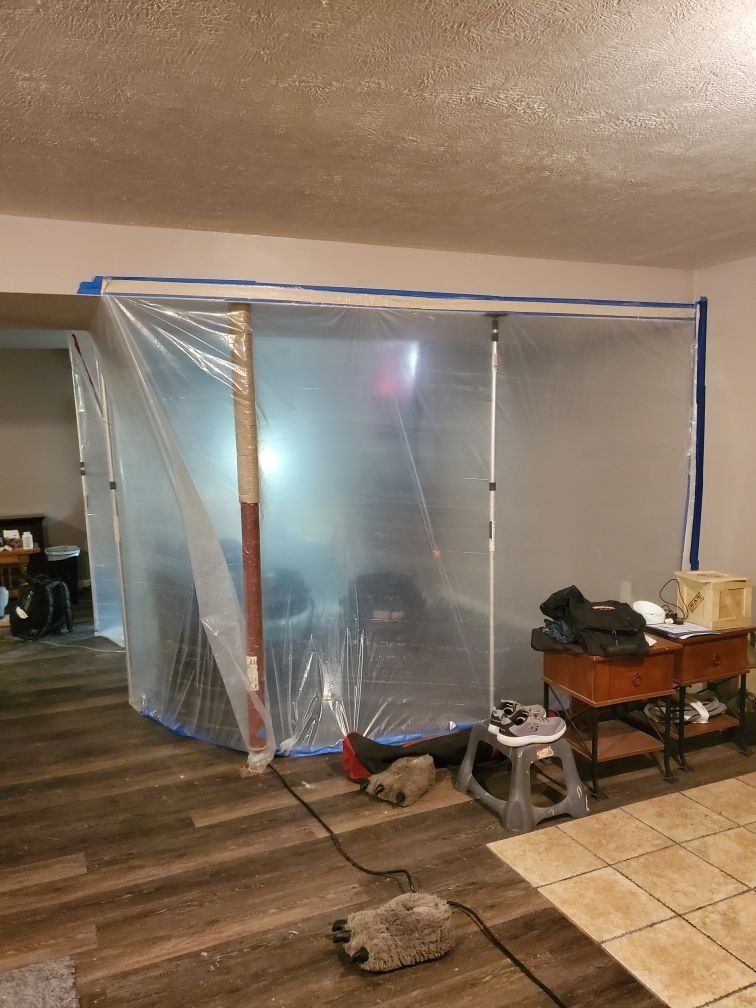 A living room with a clear plastic tarp on the wall.