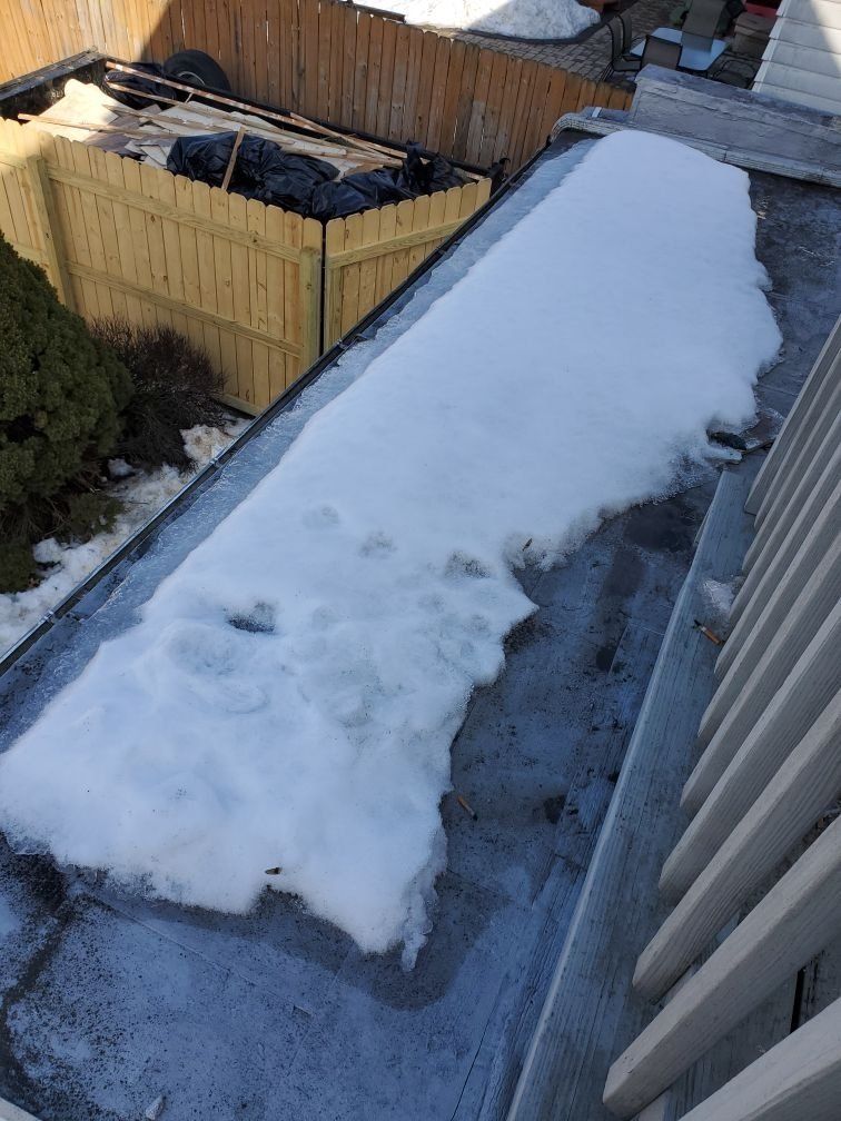 There is a lot of snow on the roof of a building.