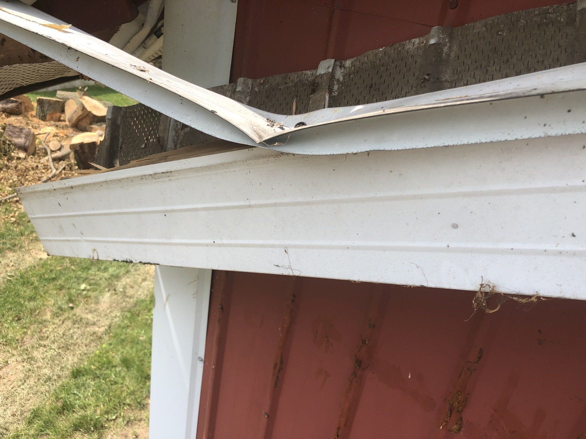 The roof of a barn that has been damaged by a tree.