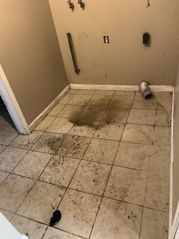 A dirty tiled floor in a room with a hole in the floor.