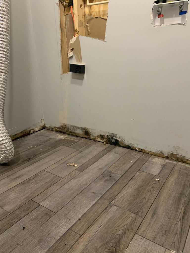 A bathroom with a wooden floor and a hole in the wall.