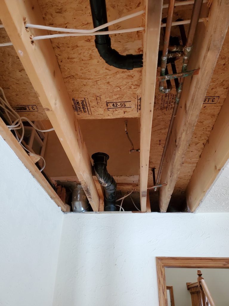 A wooden ceiling with pipes and wires coming out of it.