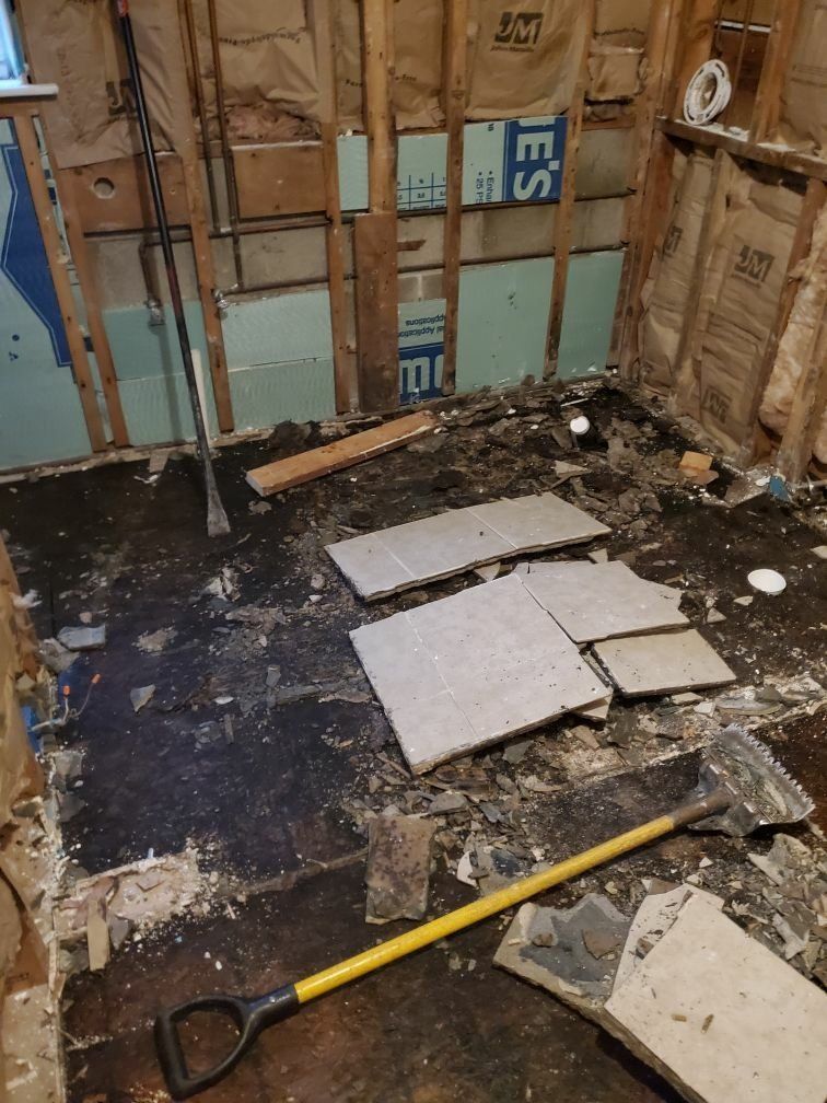 A shovel is laying on the floor of a bathroom under construction.