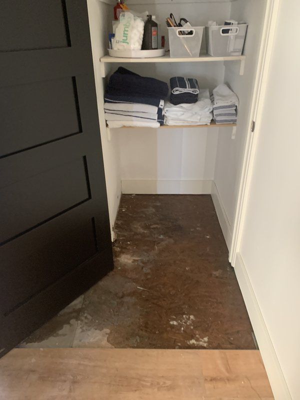 A closet with a black door and a shelf with towels on it.