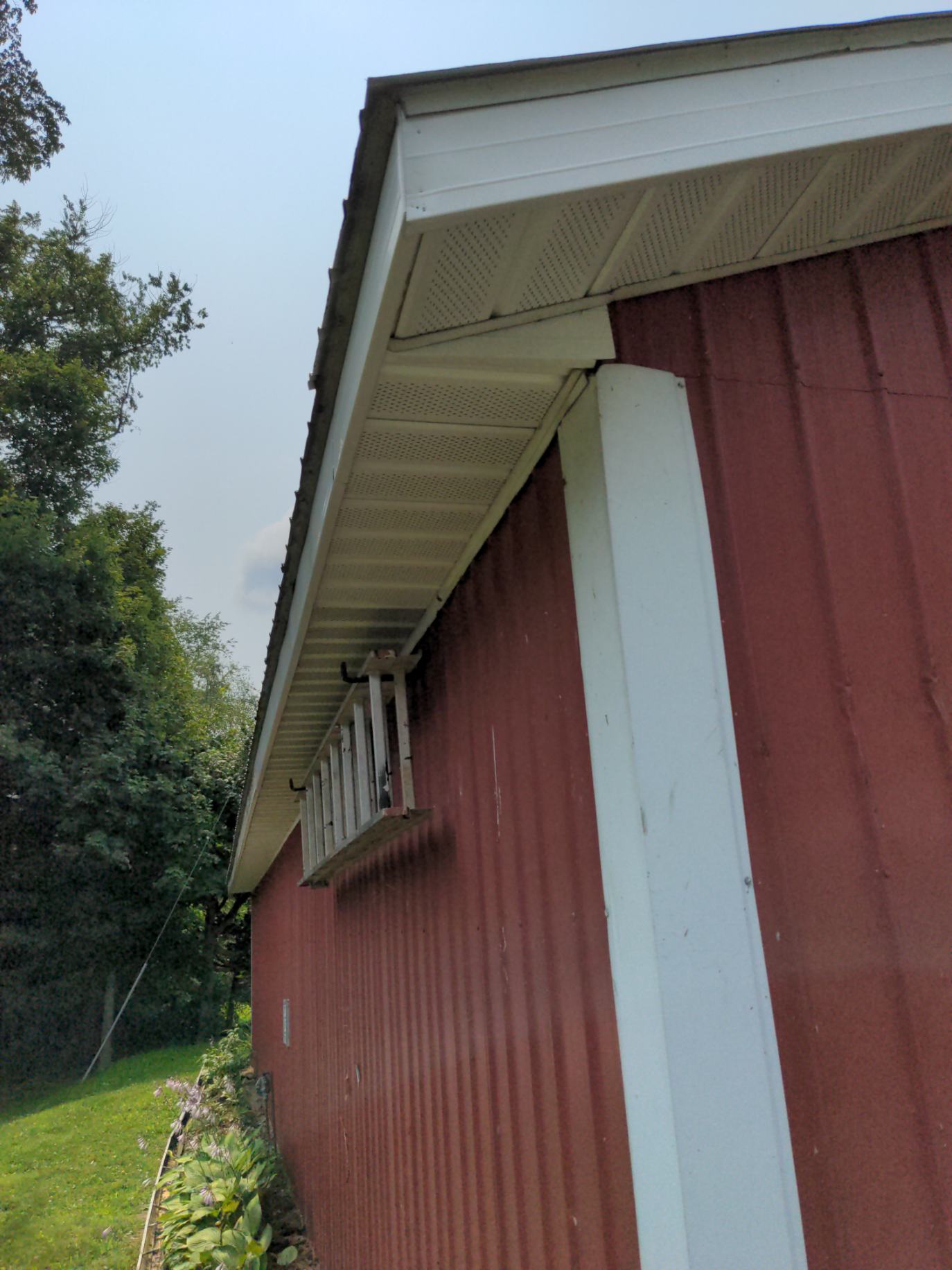A red barn with a white trim and a window on the side.