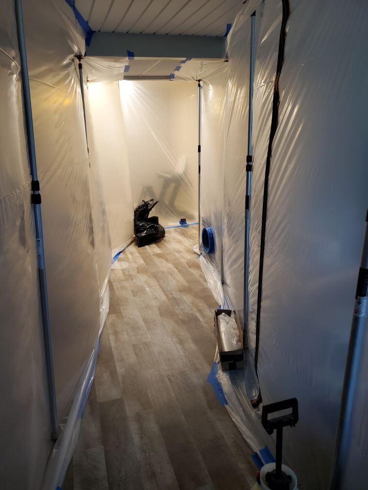 A hallway covered in plastic and industrial fan.