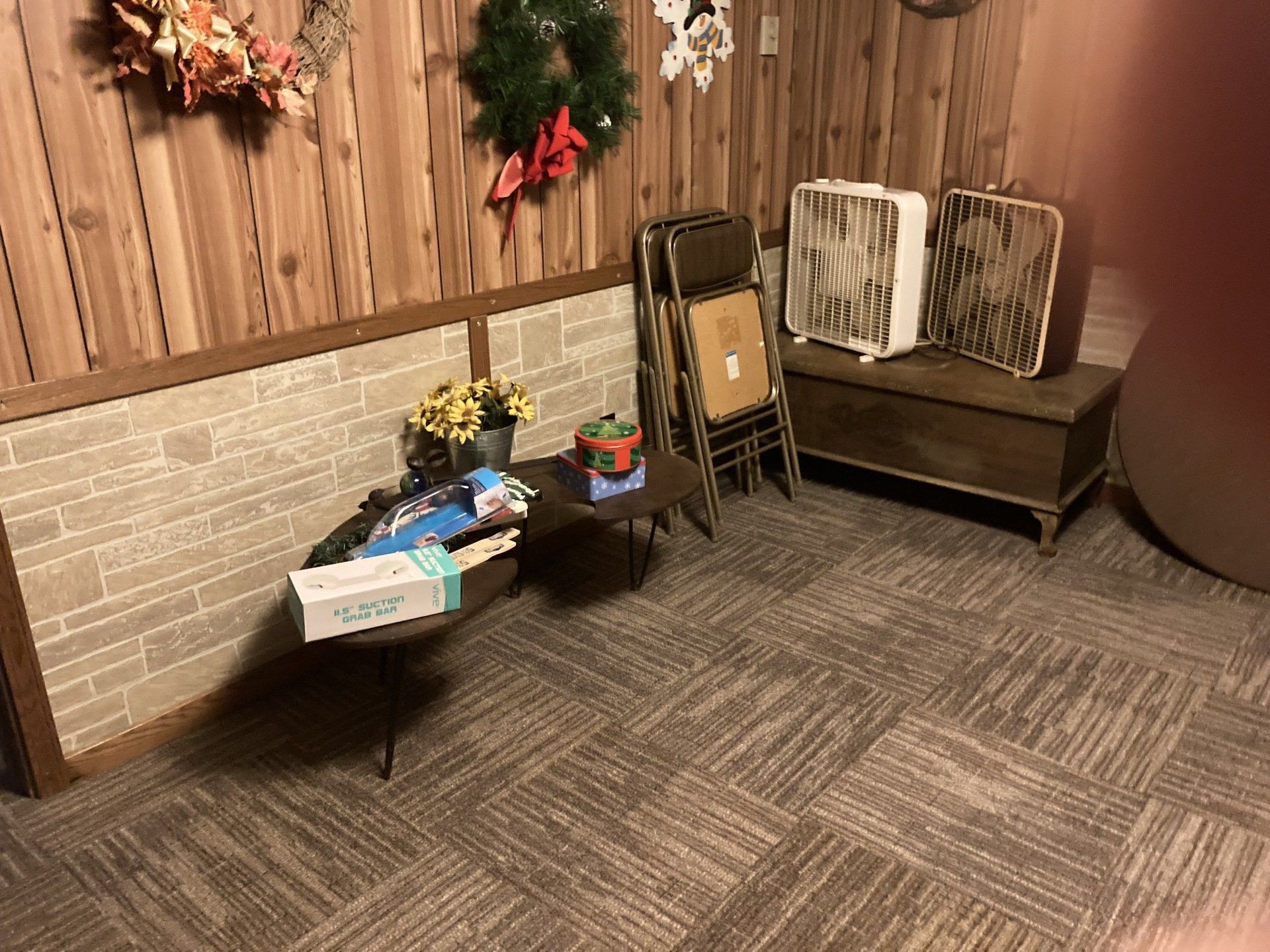 A room with a table , chairs , fans and a christmas wreath on the wall.