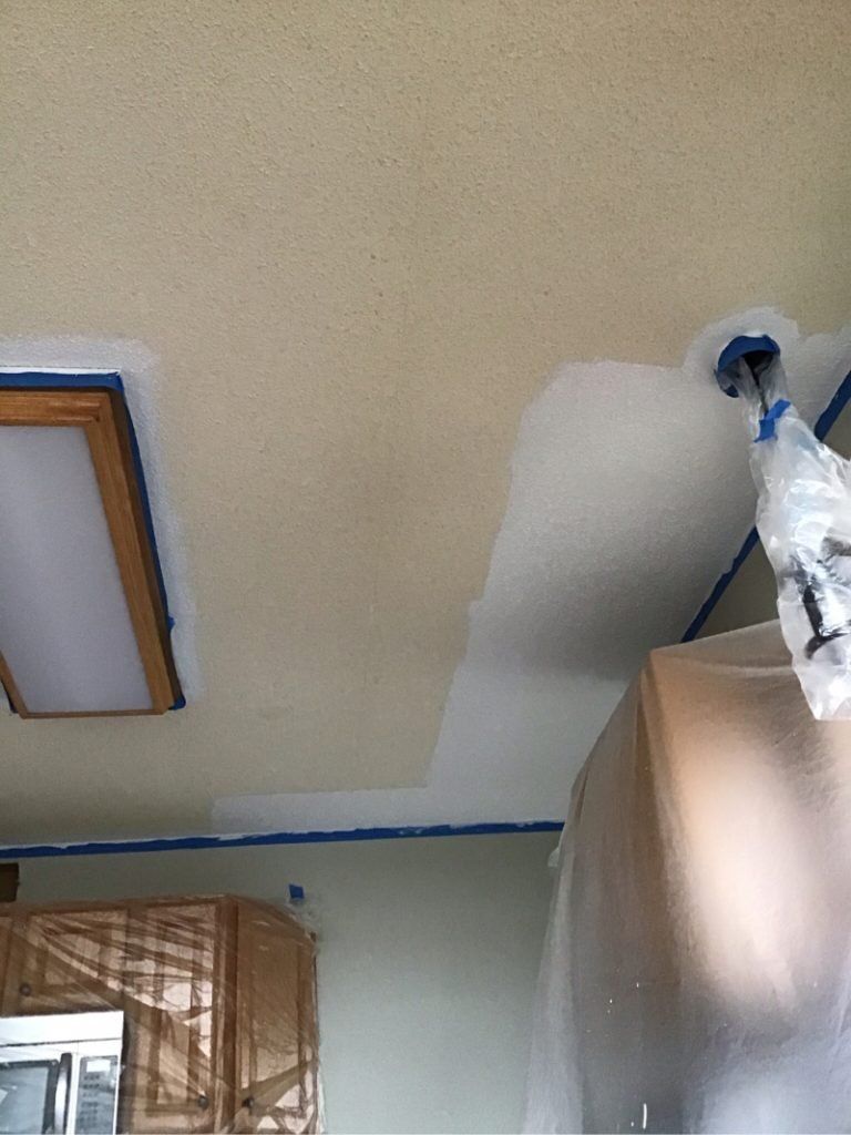 A kitchen with a ceiling that is being painted.