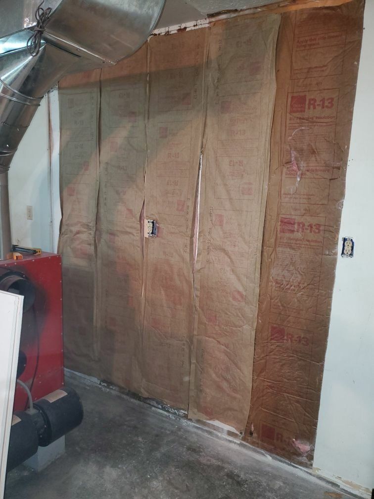A fire damaged room with a red heater and a wall covered in insulation.